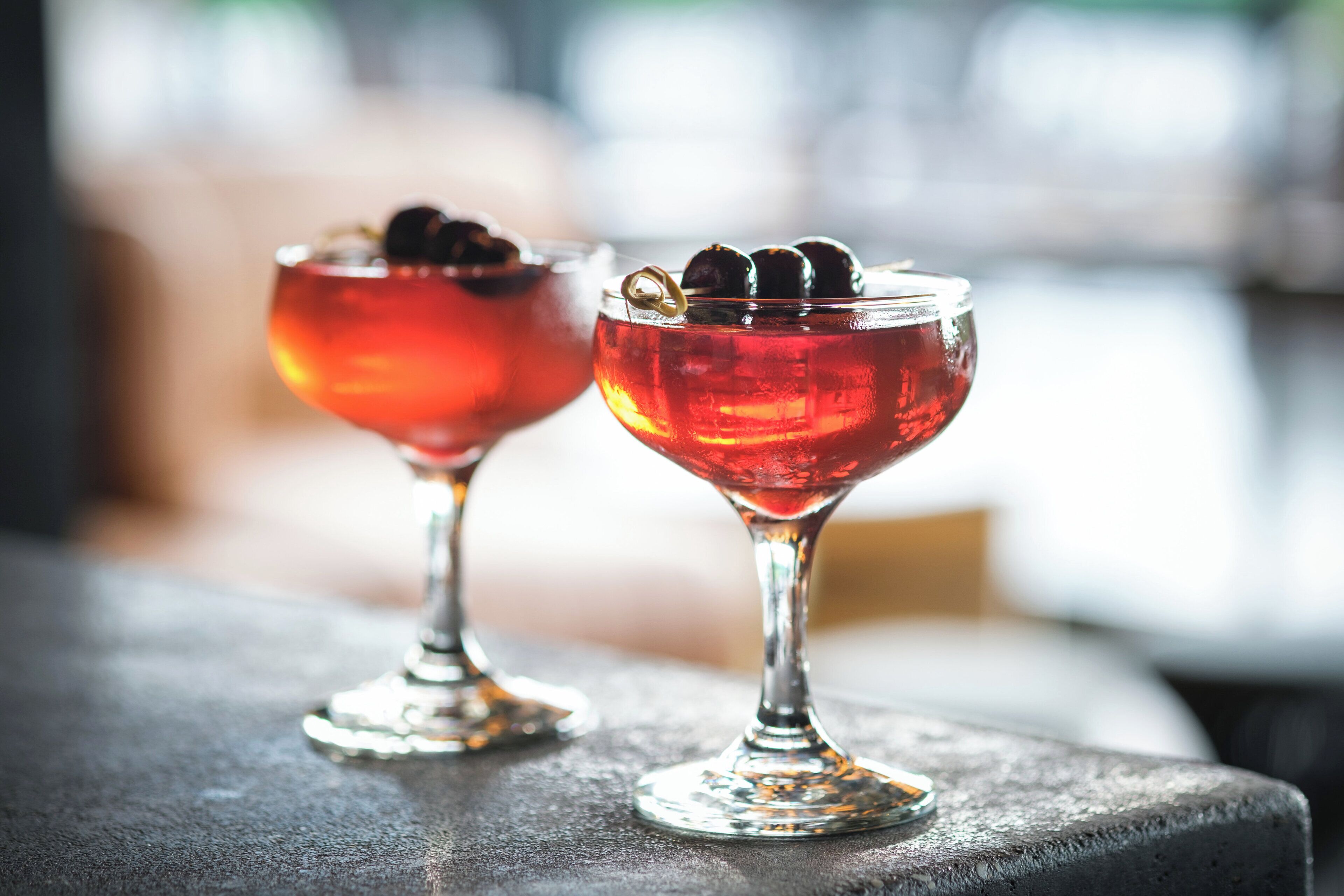 Two cocktail glasses on a textured surface.