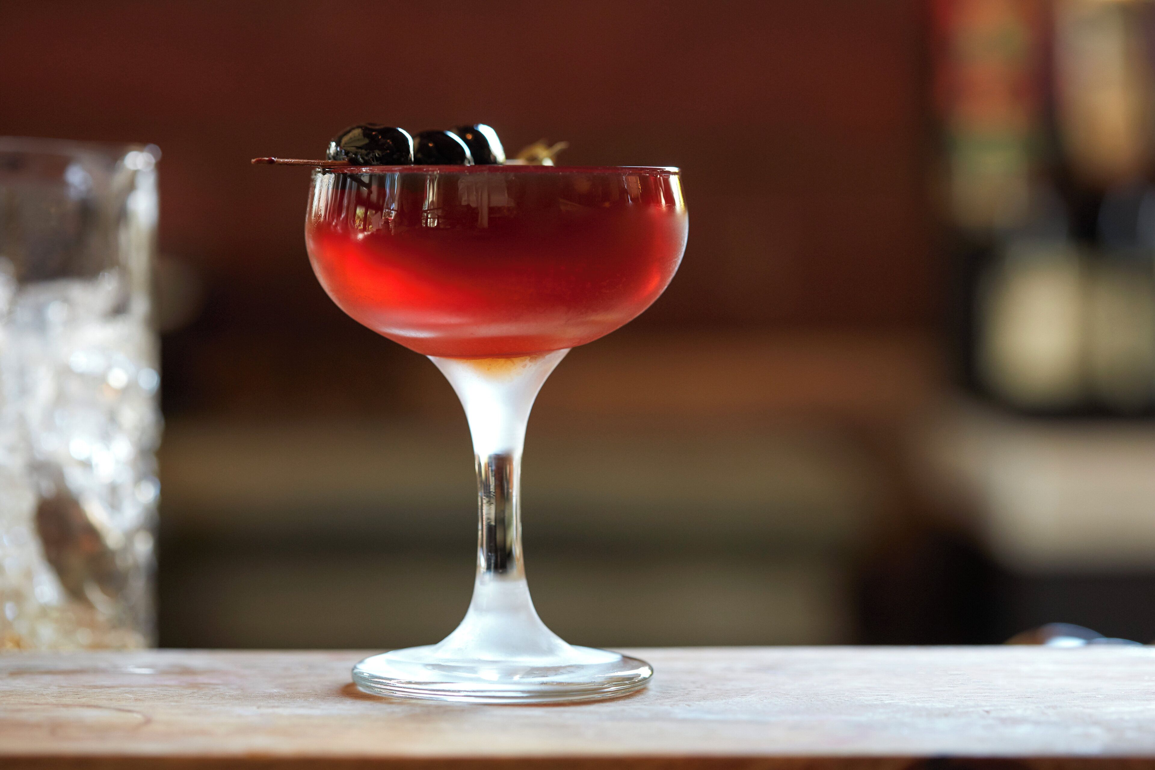 A cocktail in a stemmed glass on a wooden surface.
