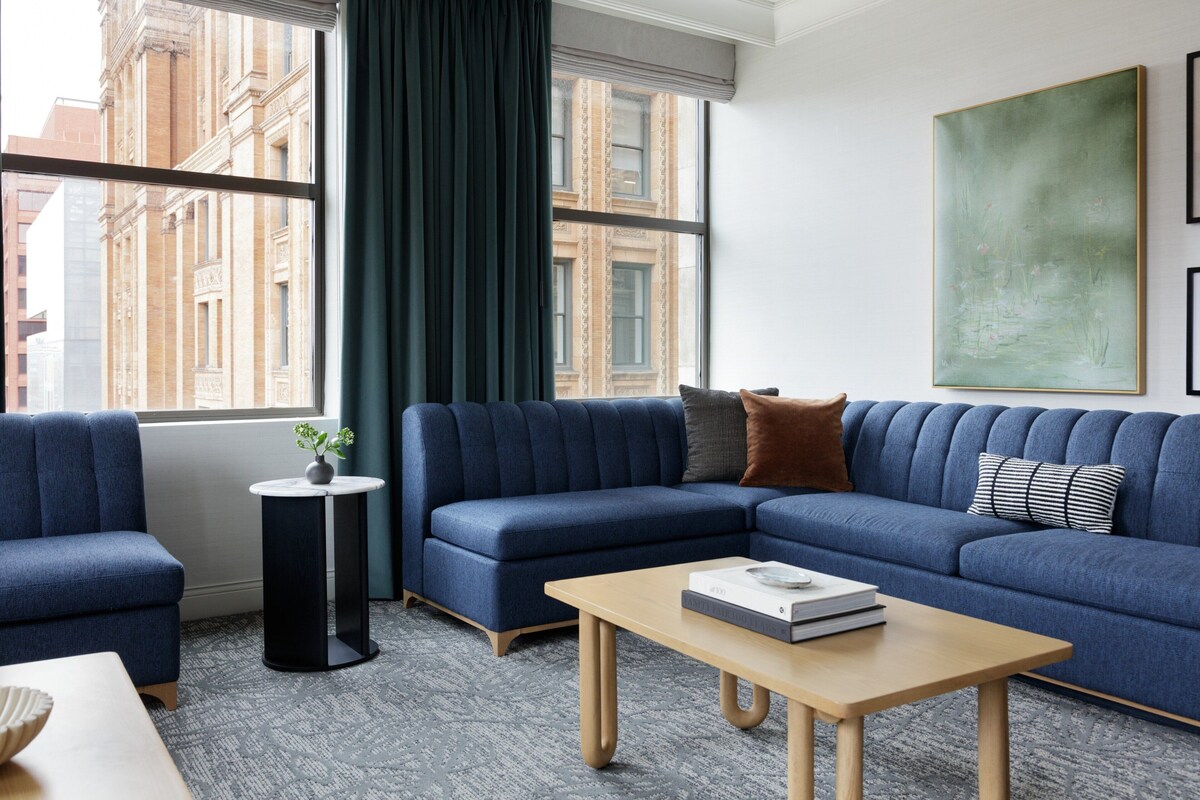 A modern living room with a blue sectional sofa, a round side table, and a coffee table.