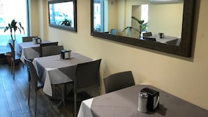 A restaurant with tables and chairs, large mirrors on the walls, and potted plants. - Hotel Oriente (Veracruz)