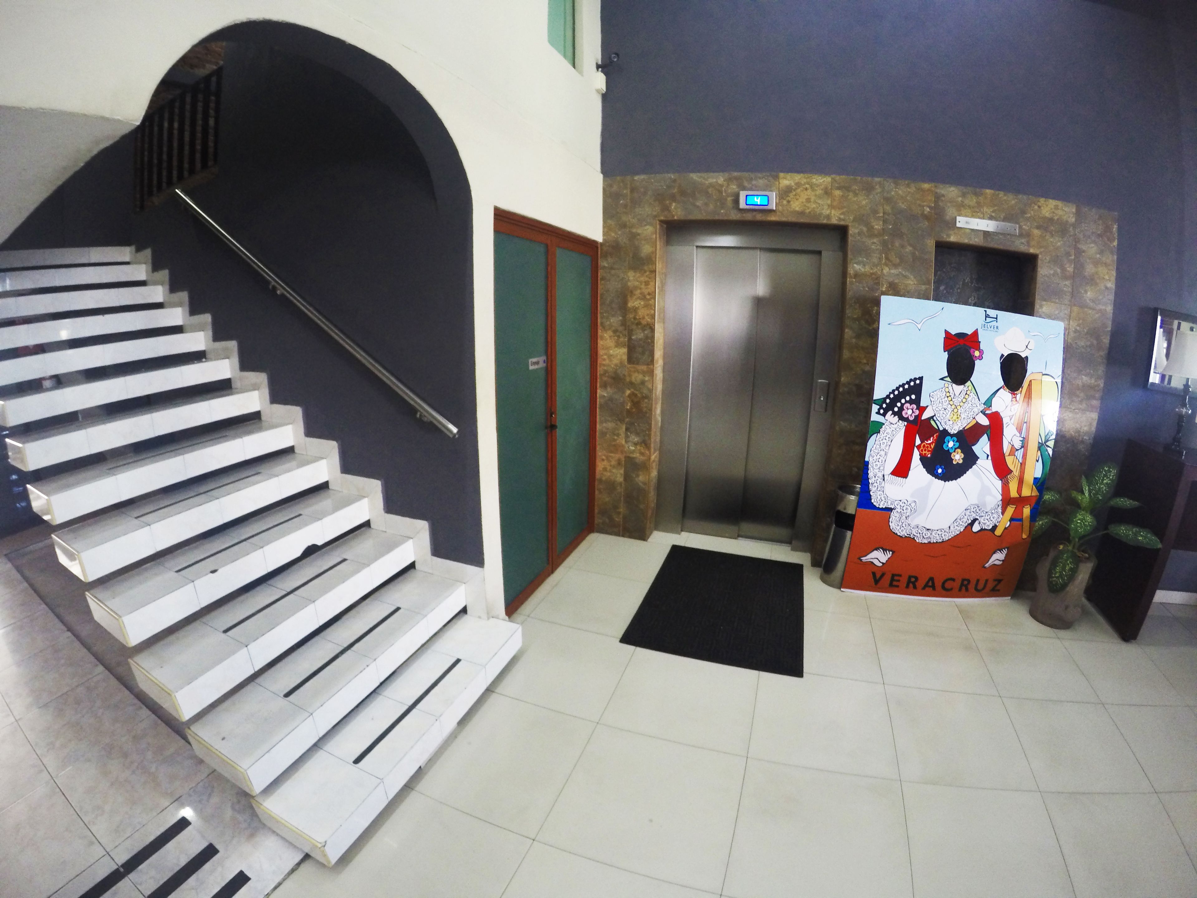 A staircase leading to an elevator, a door, and a poster with the text "VERACRUZ".