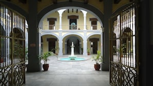 A courtyard with a central fountain, surrounded by arches and potted plants. - Hotel Oriente (Veracruz)
