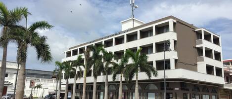 A multi-story hotel with a flat facade, palm trees in front, and a clear sky.