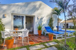Un edificio blanco con un patio amoblado, que incluye muebles de exterior y plantas en macetas.