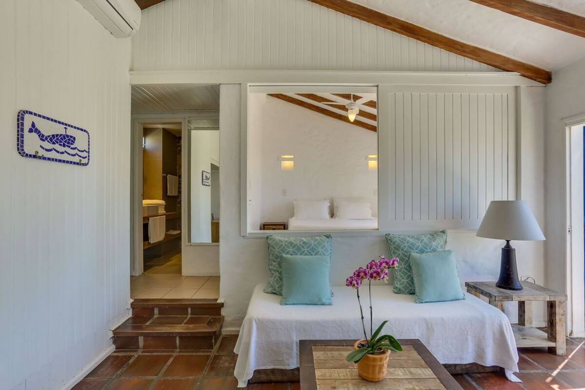 Une chambre à coucher avec un lit, deux oreillers, une table de chevet avec une lampe et une orchidée en pot.