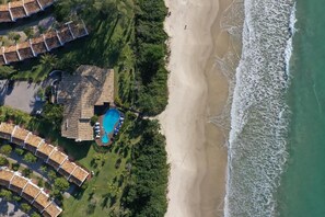 En fastighet vid kusten med en swimmingpool, tillgång till stranden och flera byggnader med tak av terrakotta.