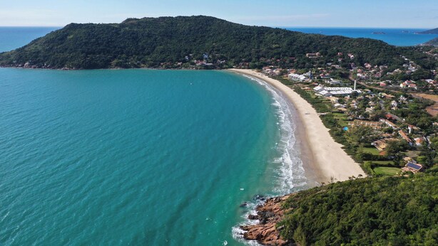 Une ville côtière avec une plage, des maisons et une colline.