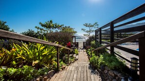 Un sentier en bois mène à une plage, sous un ciel dégagé et ensoleillé.