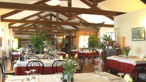 A restaurant with multiple tables, each set with cutlery and glassware, and a variety of plants and flowers as decorations.