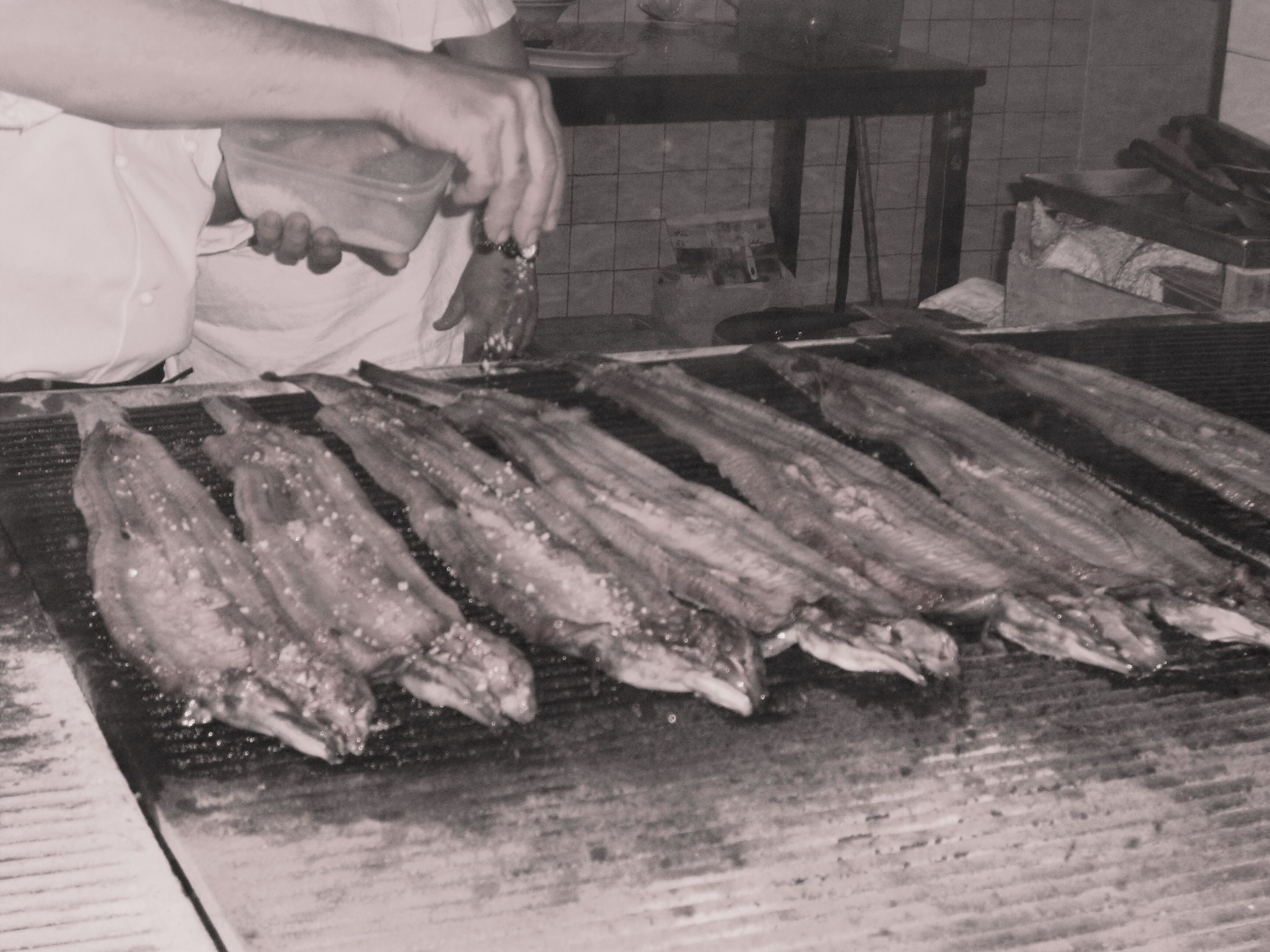Jemand grillt Fisch auf einem Grill.