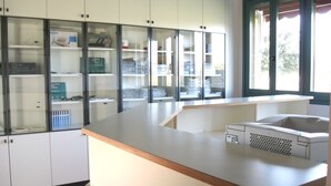 Un laboratorio con gabinetes blancos, una barra de trabajo e impresora.
