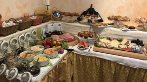 Un bufé con diversas opciones de comida, incluyendo frutas, quesos y pasteles.