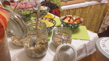 A buffet table with various food items including fruits, cheeses, and meats.