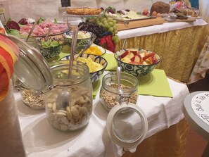 A buffet table with various food items including fruits, cheeses, and meats.