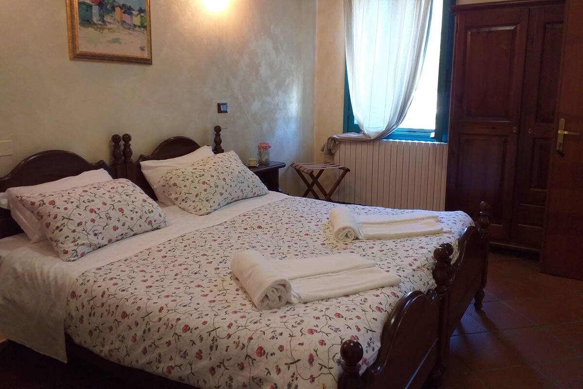 A neatly made bed with floral bedding, a bedside lamp, and a small table with a lamp.
