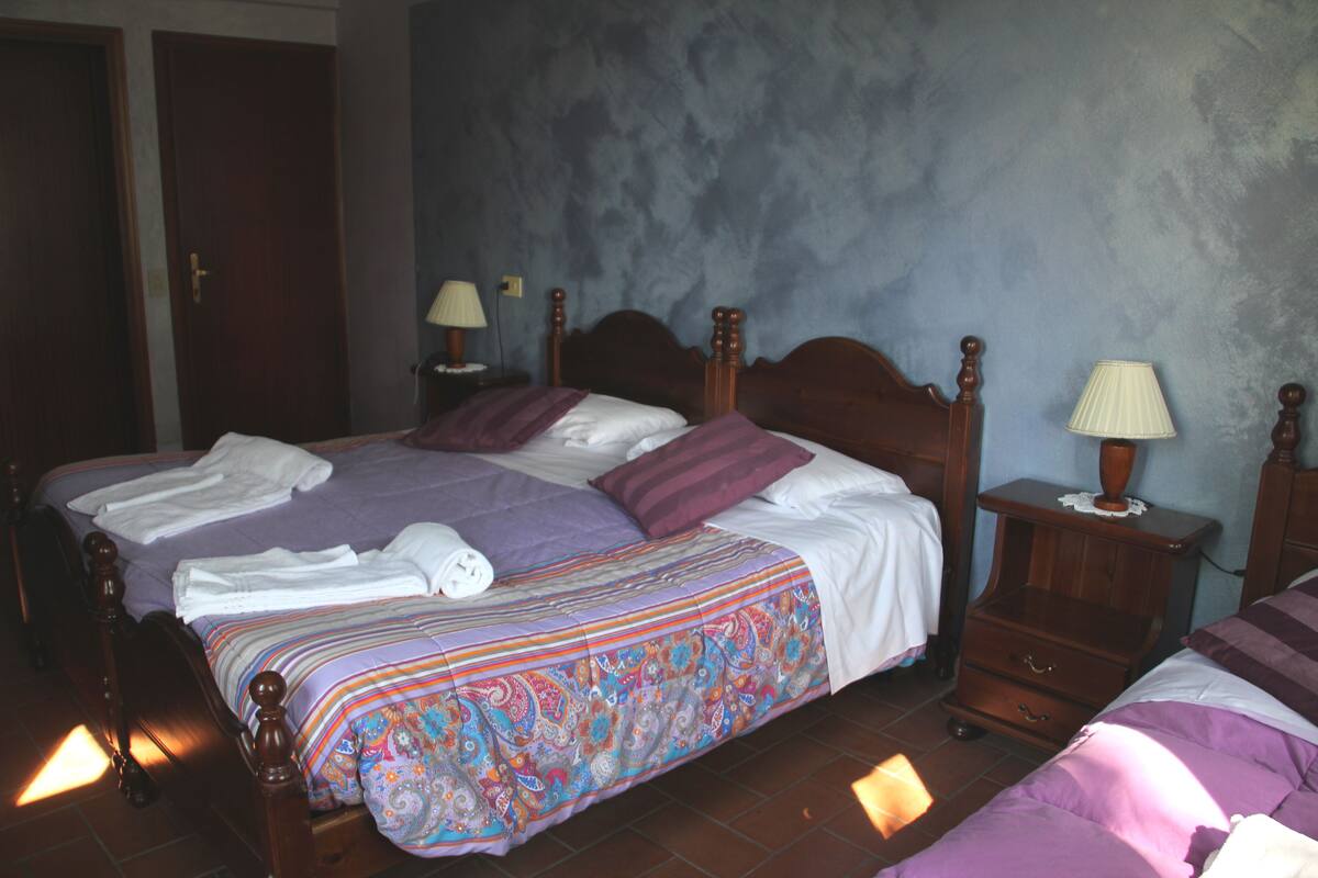 A bedroom with a large bed, a nightstand, a dresser, and a lamp.