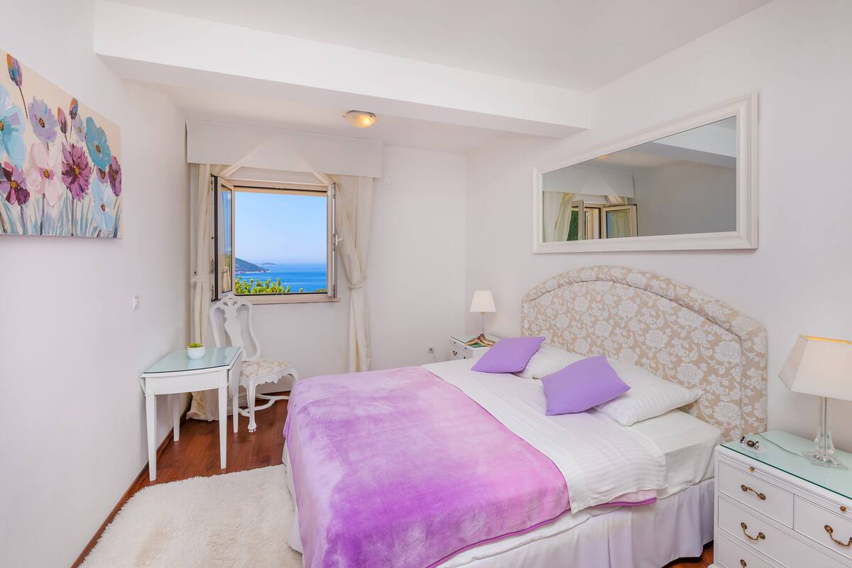Un dormitorio con cama, escritorio, silla, ventana con vistas y espejo.