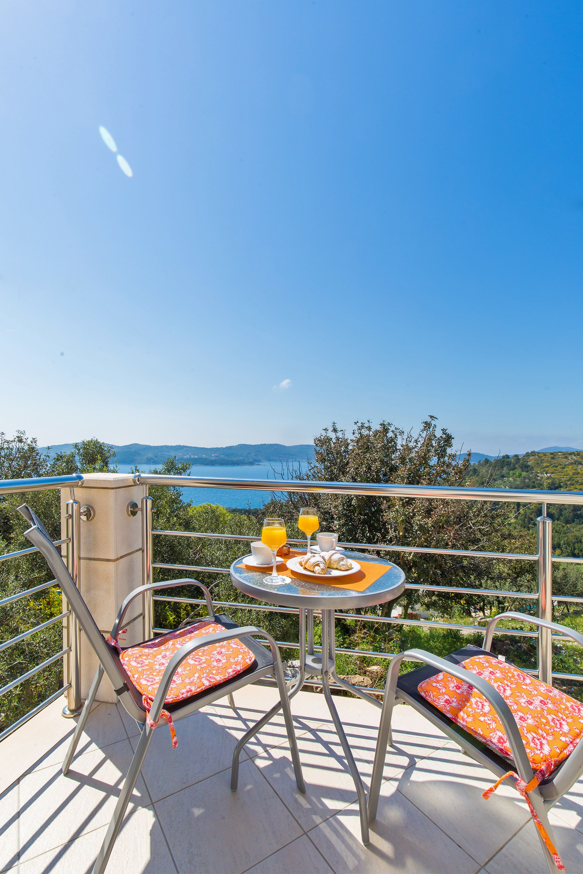 A balcony with a table set for breakfast, overlooking a scenic view.