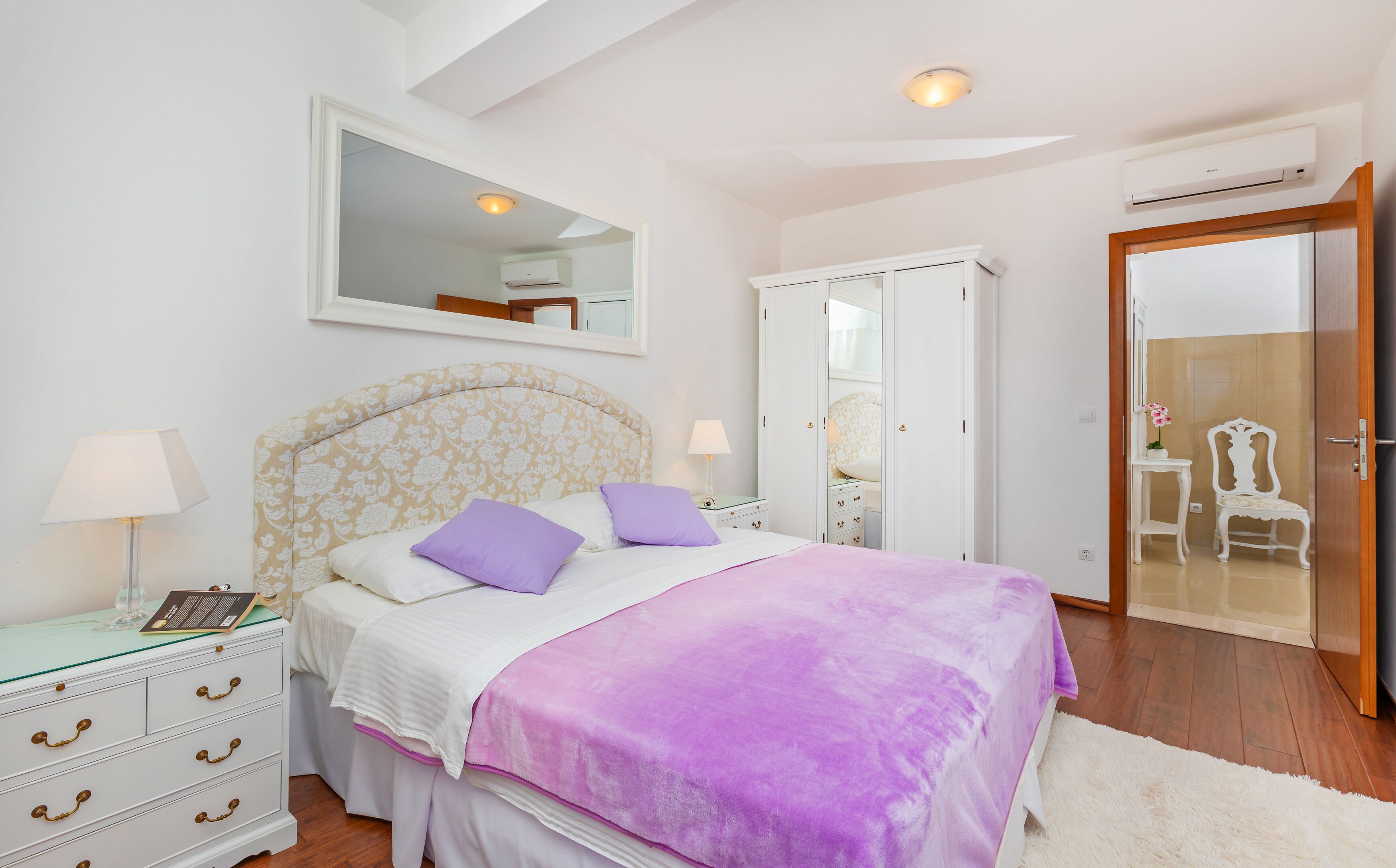 Une chambre à coucher comprenant un lit, des tables de chevet, une armoire et un appareil de climatisation.