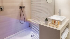 A modern bathroom with a glass shower enclosure, a vanity with a mirror, and a sink. - Manfredi Luxury Apartments (Rome)