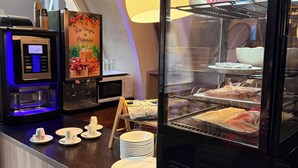 Una estación de café con una máquina de café KREa, una vitrina de vidrio con pasteles, y un letrero que dice 'Les Vergeres de Philomène'.