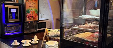 A coffee station with a KREa coffee machine, a glass display case with pastries, and a sign reading 'Les Vergeres de Philomène.'