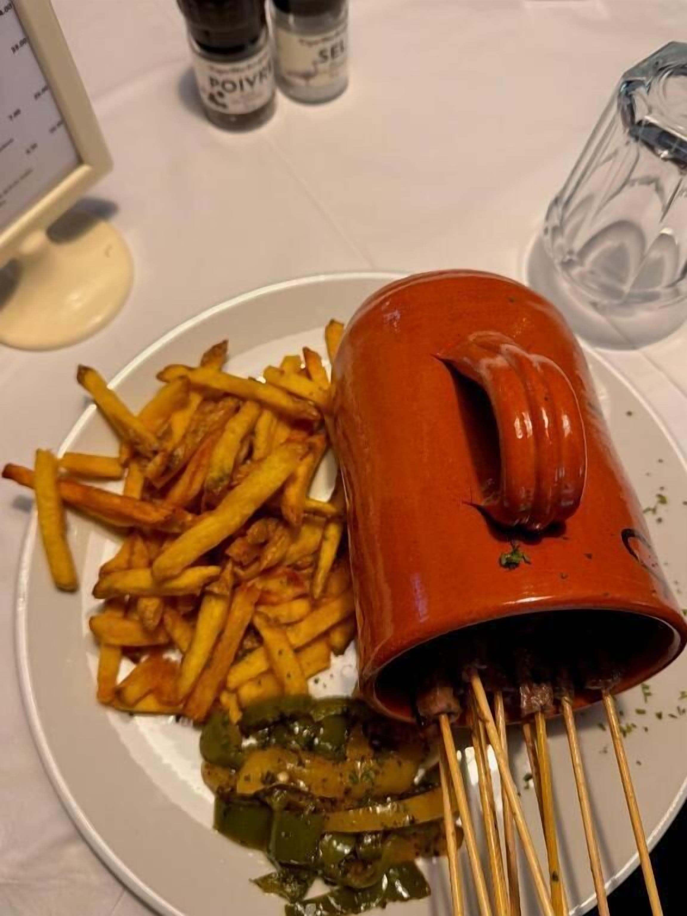 Un plato con papas fritas, un plato de verduras ensartadas y un recipiente rojo.