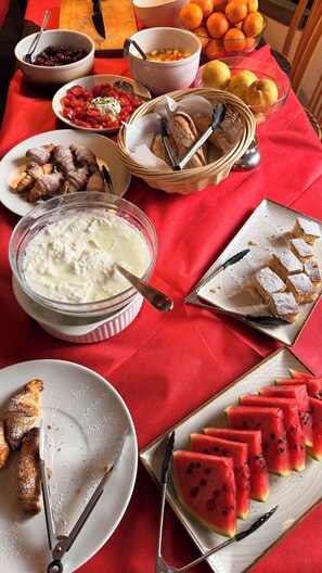 Una mesa con diferentes alimentos, como pan, fruta y un bol de crema.
