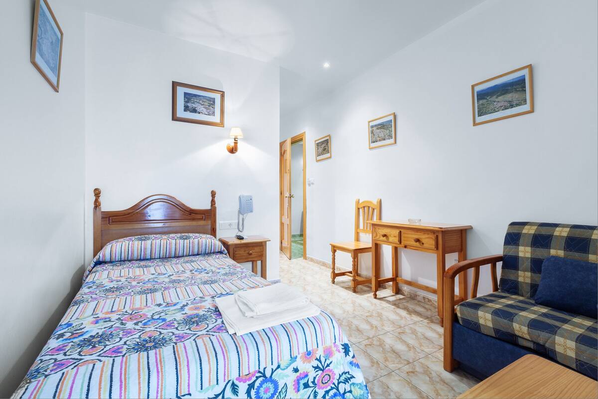 Ein Schlafzimmer mit Bett, Schreibtisch, Stuhl und Sofa.