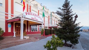 The exterior of the Philadelphia Hotel with a red and white facade, a signboard, and a flag. - Hotel Philadelfia (Peligros)