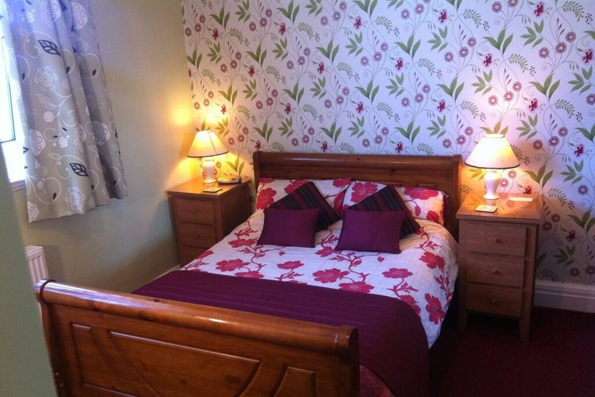 A wooden bed with a floral bedspread and two bedside lamps.