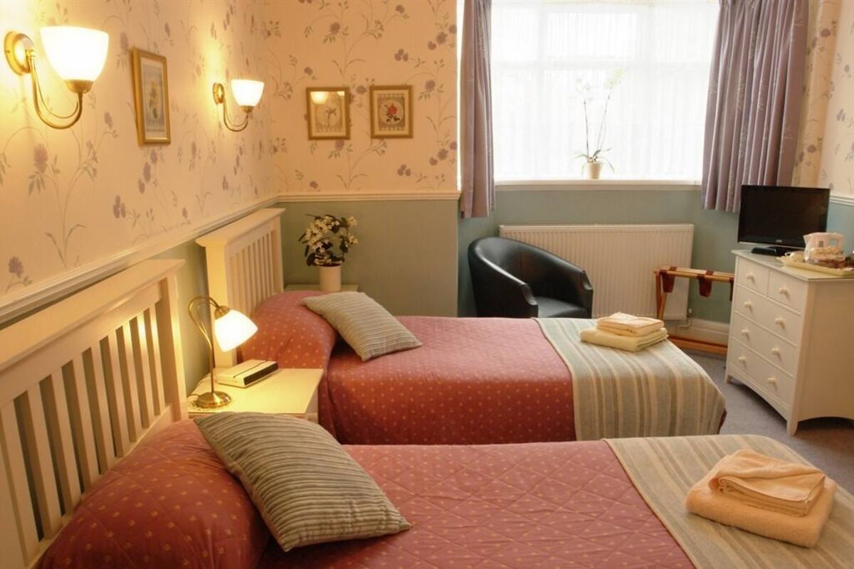 A room with two beds, a desk, a chair, and a television.