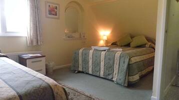A bedroom with a bed, bedside table, lamp, and a window with curtains.