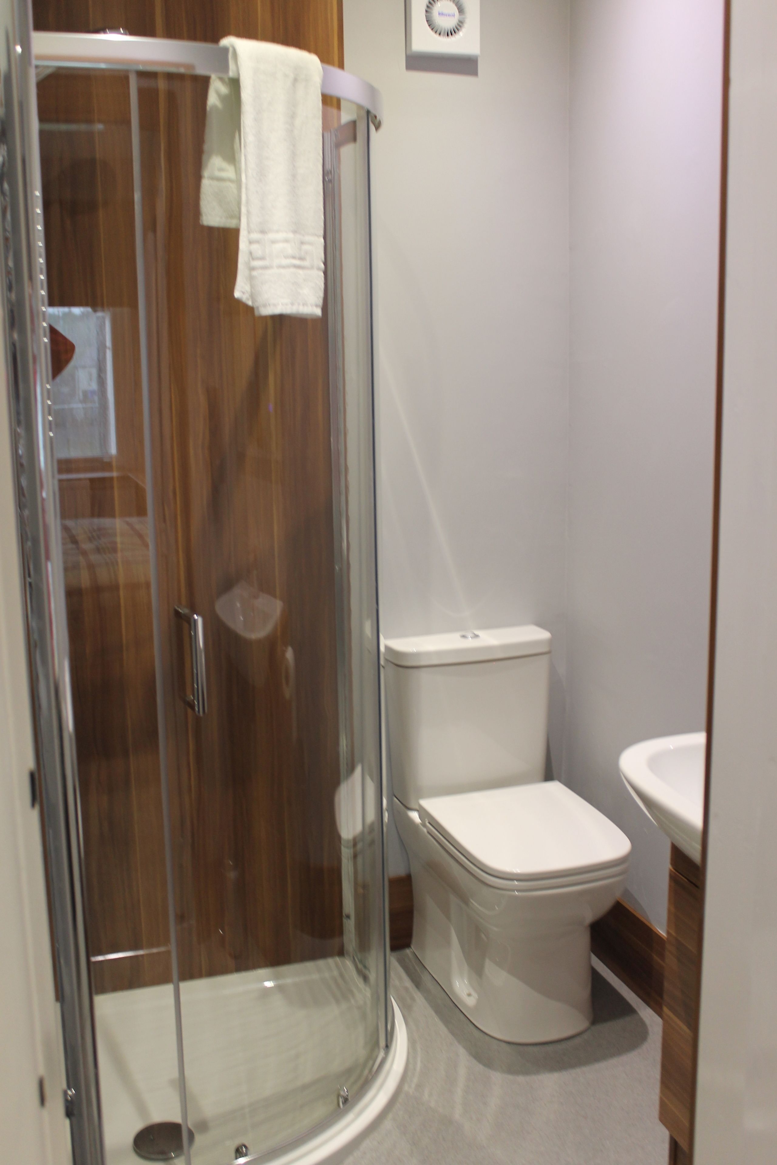 Un baño con ducha de vidrio, inodoro blanco y lavamanos.