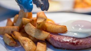 Un plato con un huevo frito, tocino y papas fritas doradas.
