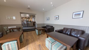 Un vaste espace de vie doté d’un plancher en bois, d’un canapé en cuir marron, de fauteuils à rayures et d’une table basse en bois.