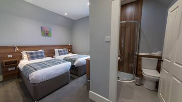 A bedroom with two beds, a shower, and a toilet.