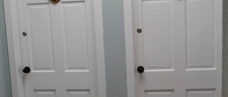 Two white doors with a police badge emblem, a checkered floor, and a plain wall.