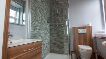 Une salle de bain moderne avec une douche à parois de verre, un meuble-lavabo en bois et des toilettes.