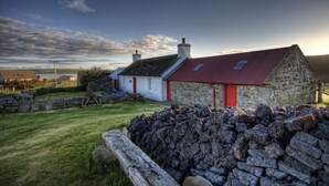 Une maison en pierre avec un toit rouge et un petit jardin.