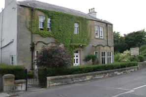 A two-story building with a sign indicating it is a guest house.