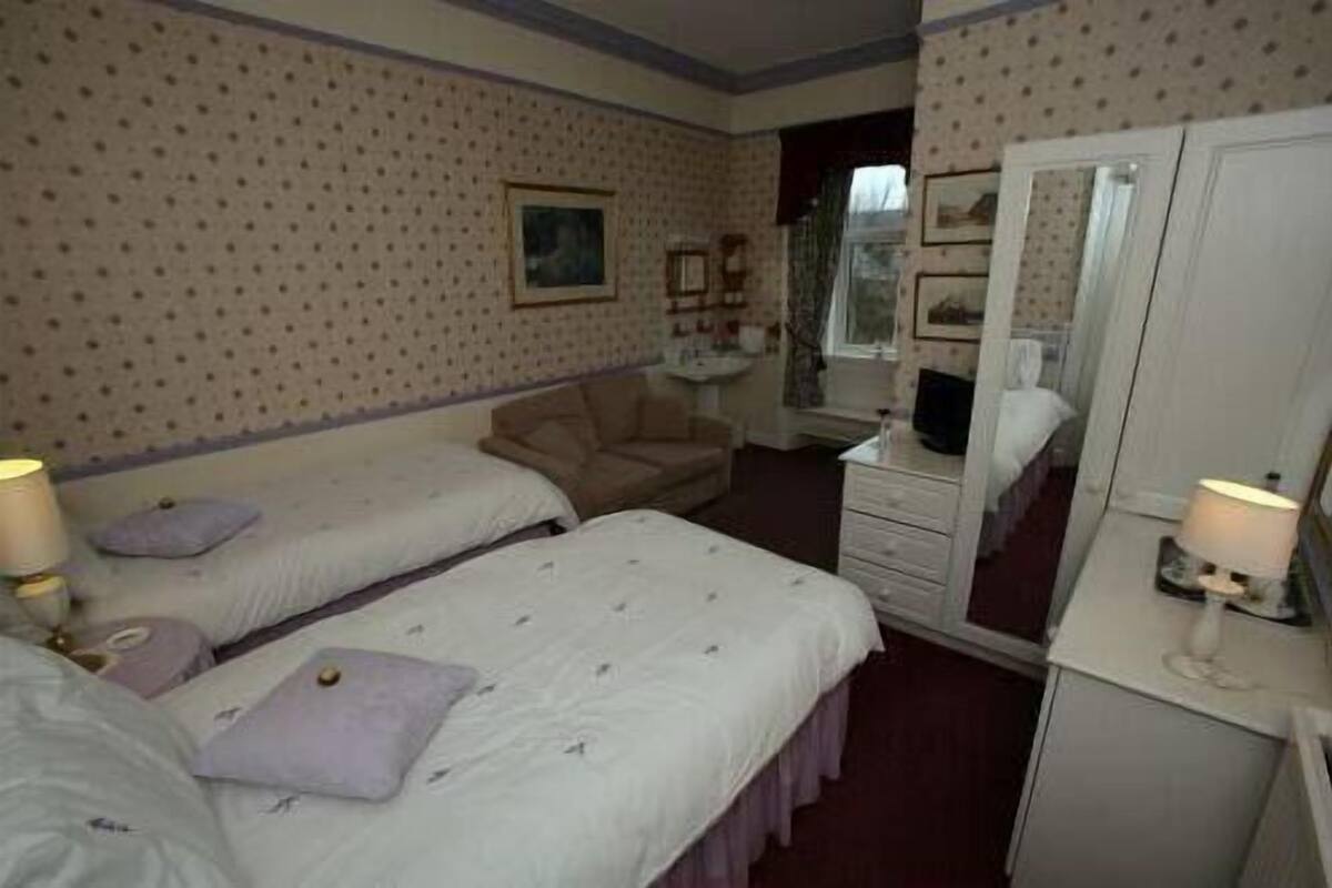 Een hotelkamer met twee eenpersoonsbedden, een bureau, een stoel, een kledingkast en een spiegel.
