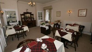 A dining area with multiple tables set for meals, a chandelier, and a mirror. - Bellevue Guest House (Kelso)
