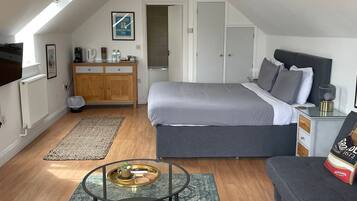 Een moderne loft slaapkamer met dakraam, groot bed, een bank, een tafeltje en een kast.