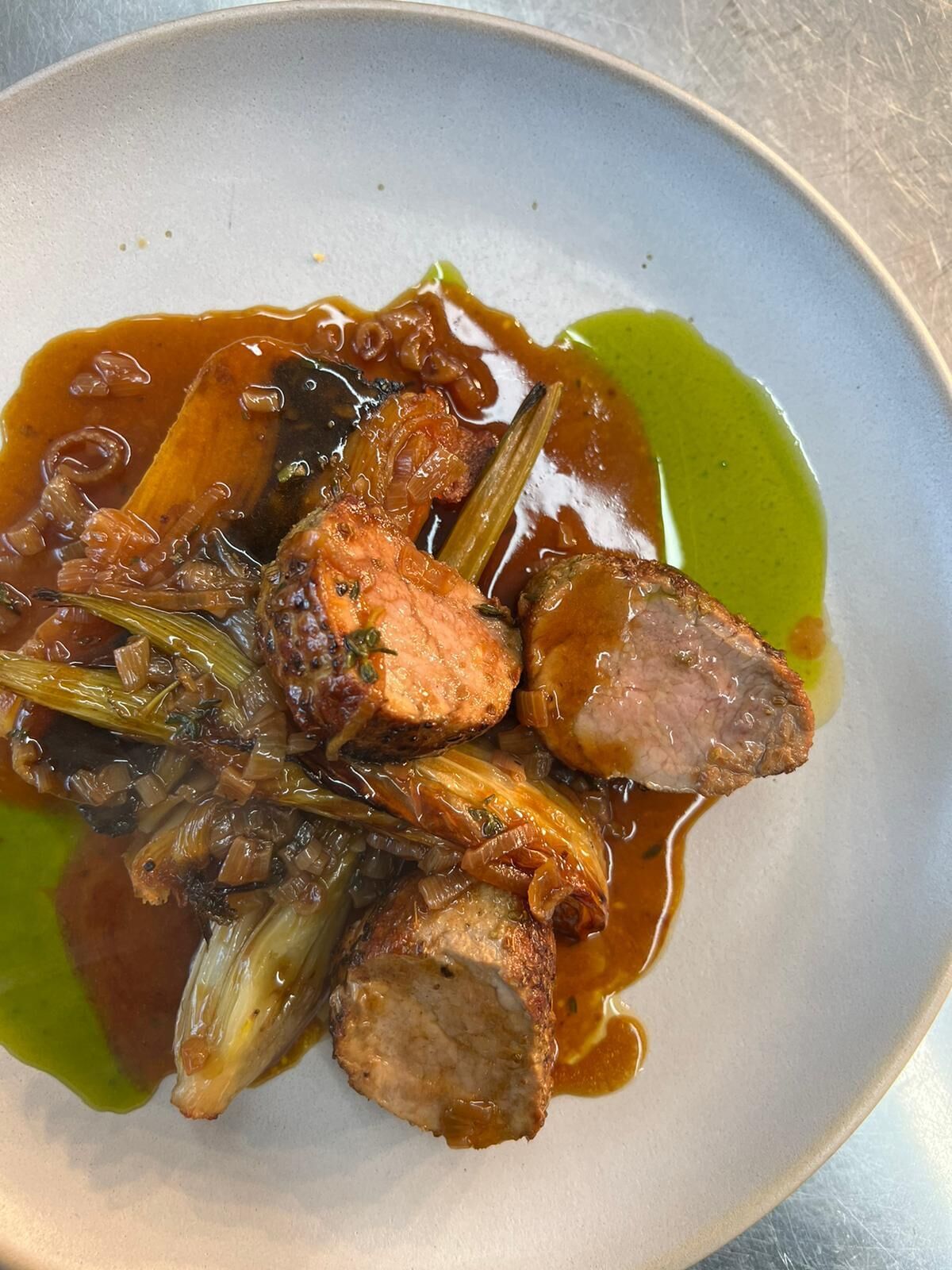 A plate of food with meat and vegetables in a sauce.