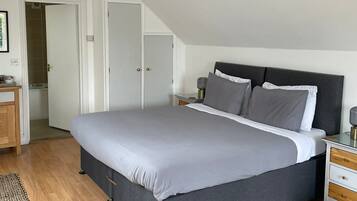 Een slaapkamer met een groot bed, een nachtkastje en een deur naar de badkamer.