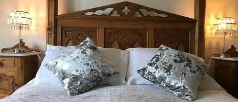 A bed with a wooden headboard, two matching pillows, and bedside lamps.