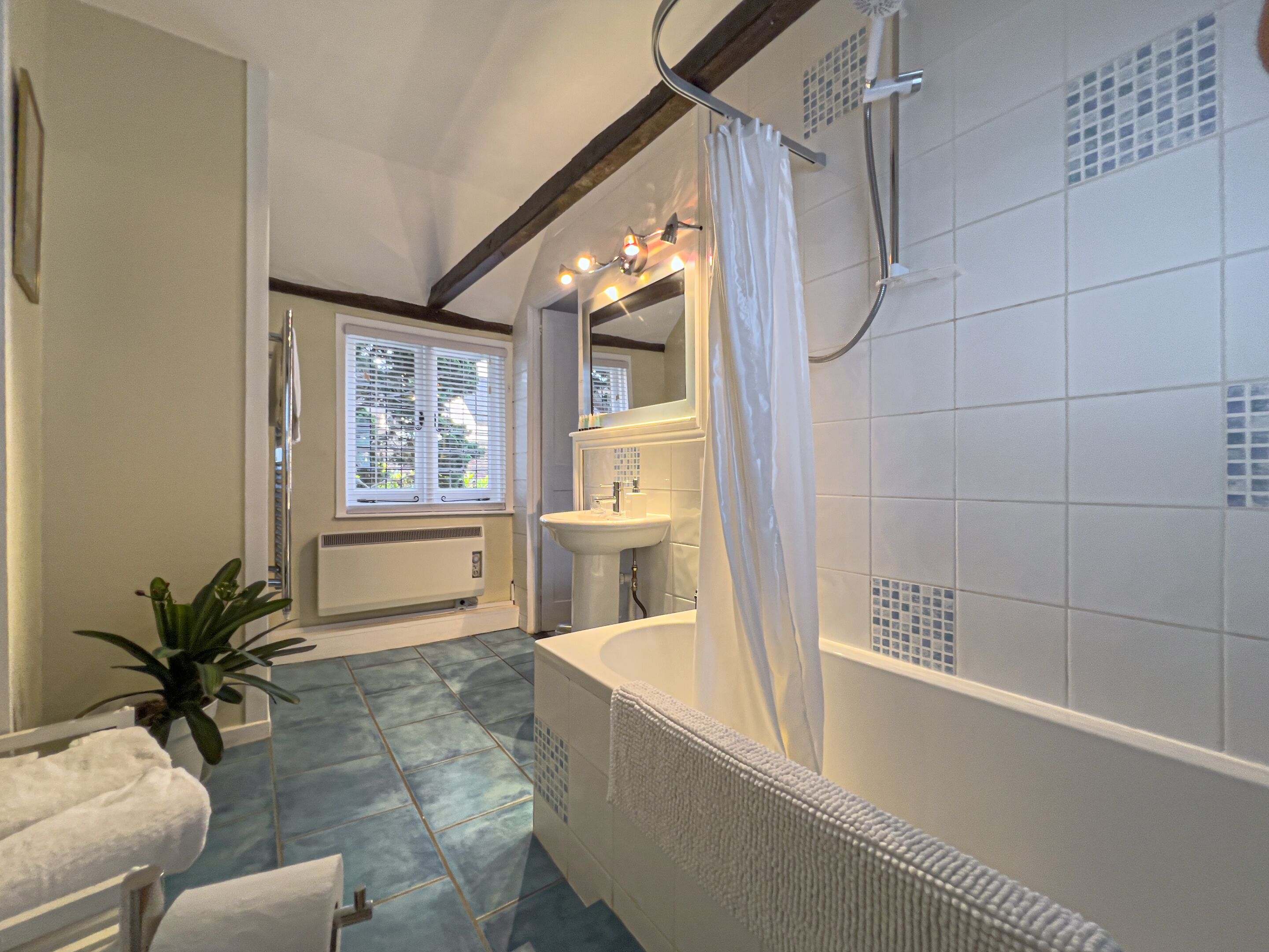 A bathroom with a bathtub, a sink, and a window with blinds.