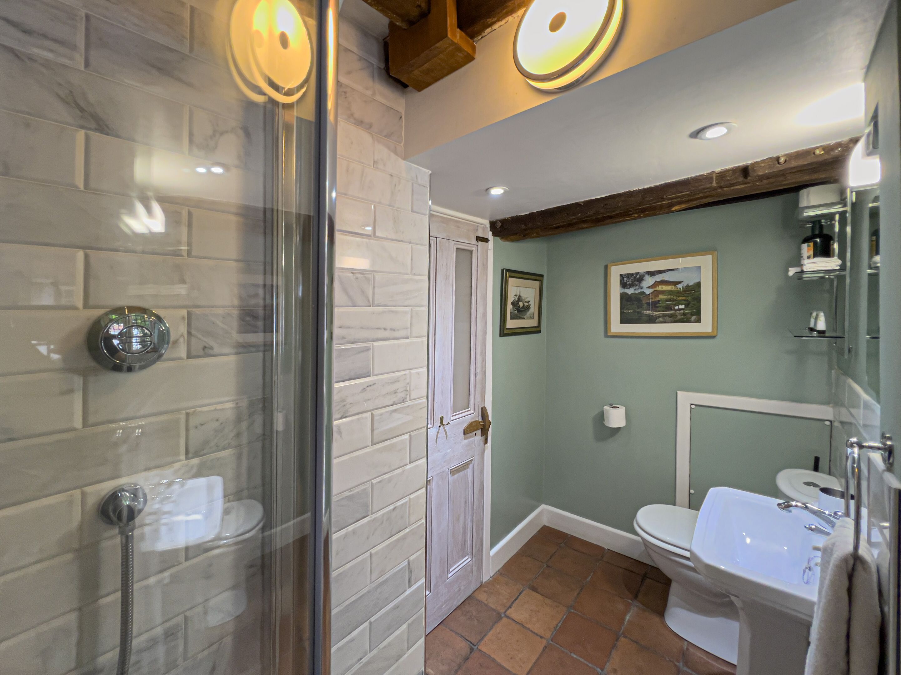 A bathroom with a glass-enclosed shower, a white toilet, and a sink with a mirror.