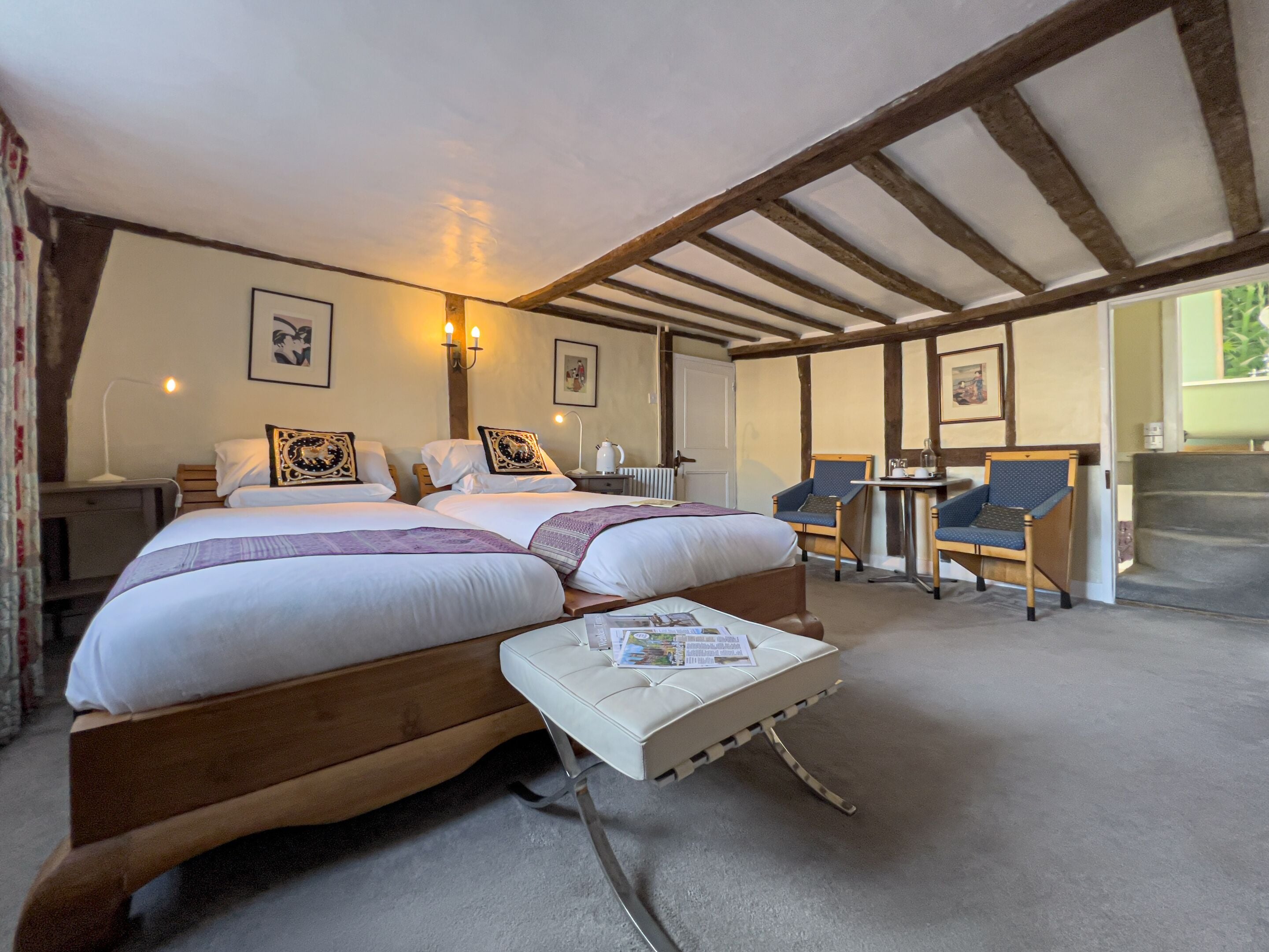 A bedroom with two beds, a small table, two chairs, and a radiator.